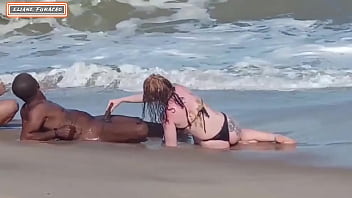 A couple engages in public sex with a stranger on the beach, allowing both partners to participate